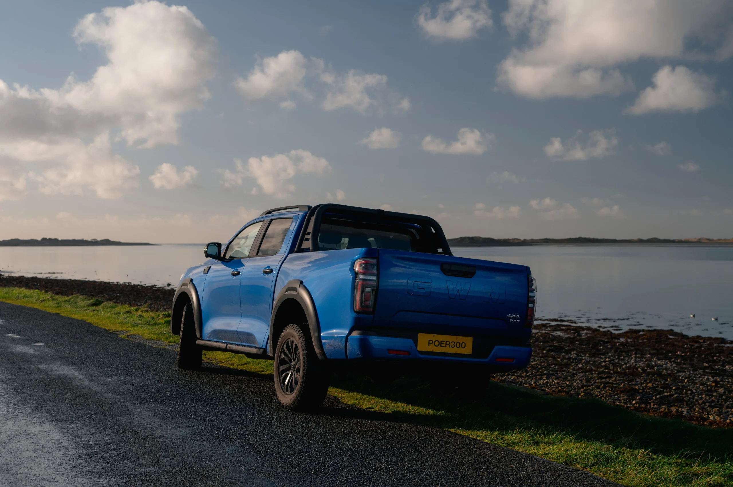 Blue GWM POER 300 driving along lake. 